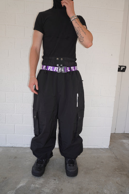 Person wearing a black outfit with a purple belt on a tiled floor.
